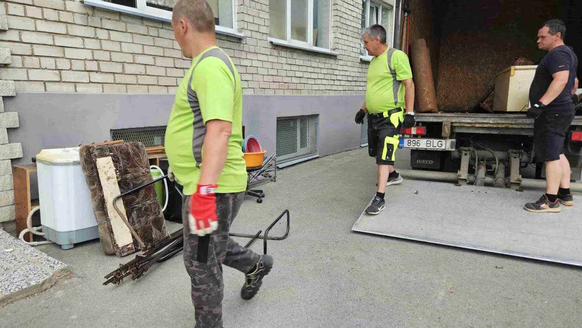 Грузчики выносят старые вещи из дома к грузовику