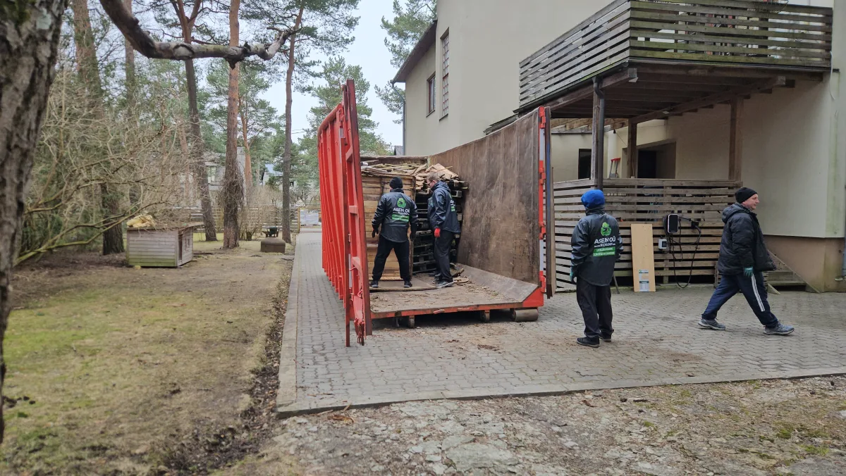 Грузчики стоят в красном контейнере во дворе у дома
