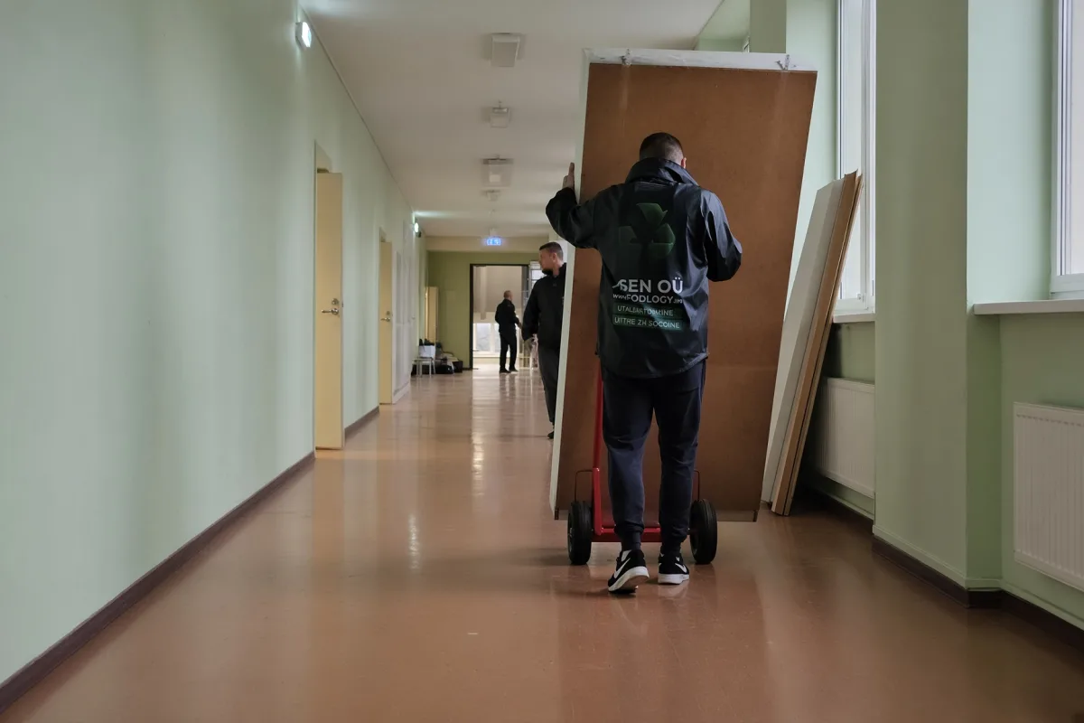 Грузчик везёт деревянные щиты на тележке по коридору