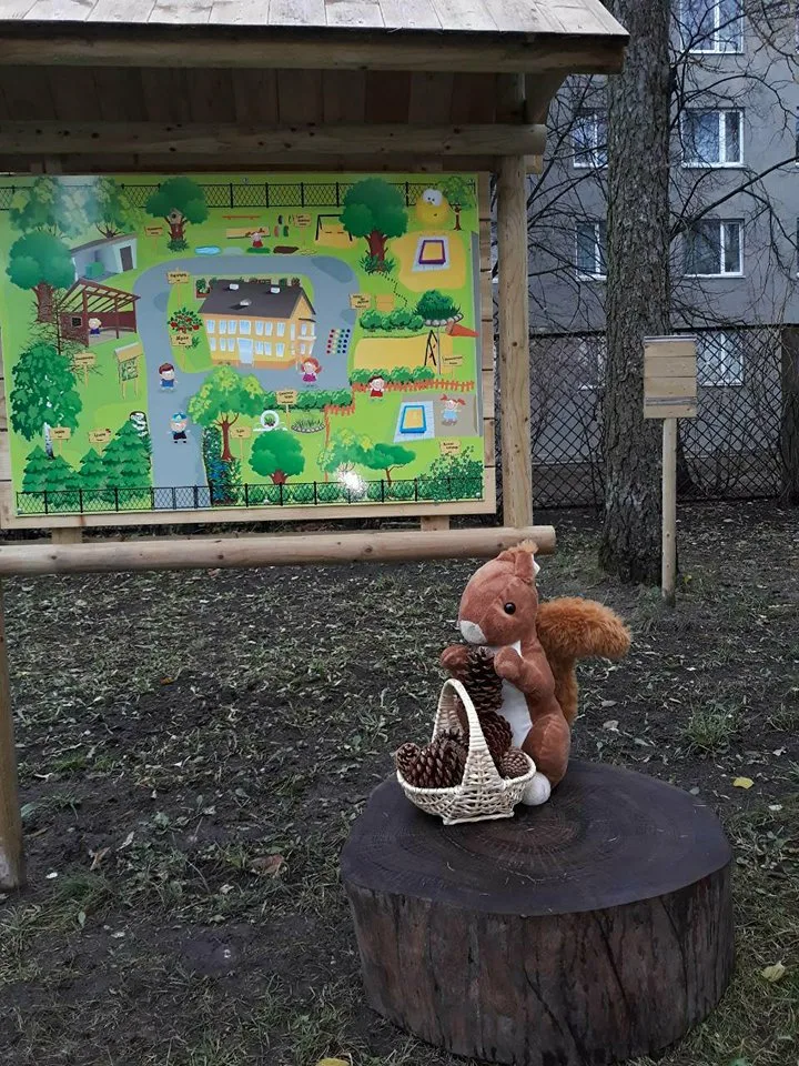 Игрушечная белка с шишками на пне во дворе садика