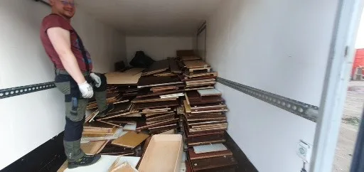 Грузчик в кузове микроавтобуса, загруженного мебельными щитами