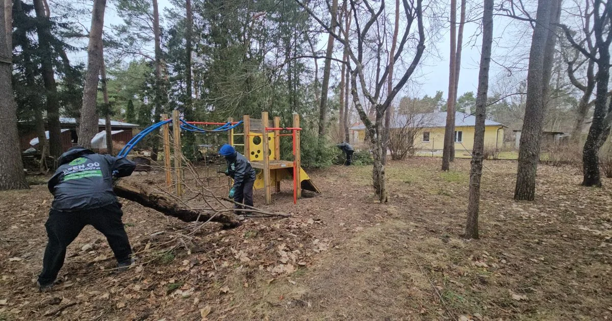 Работник тащит бревно мимо детской площадки
