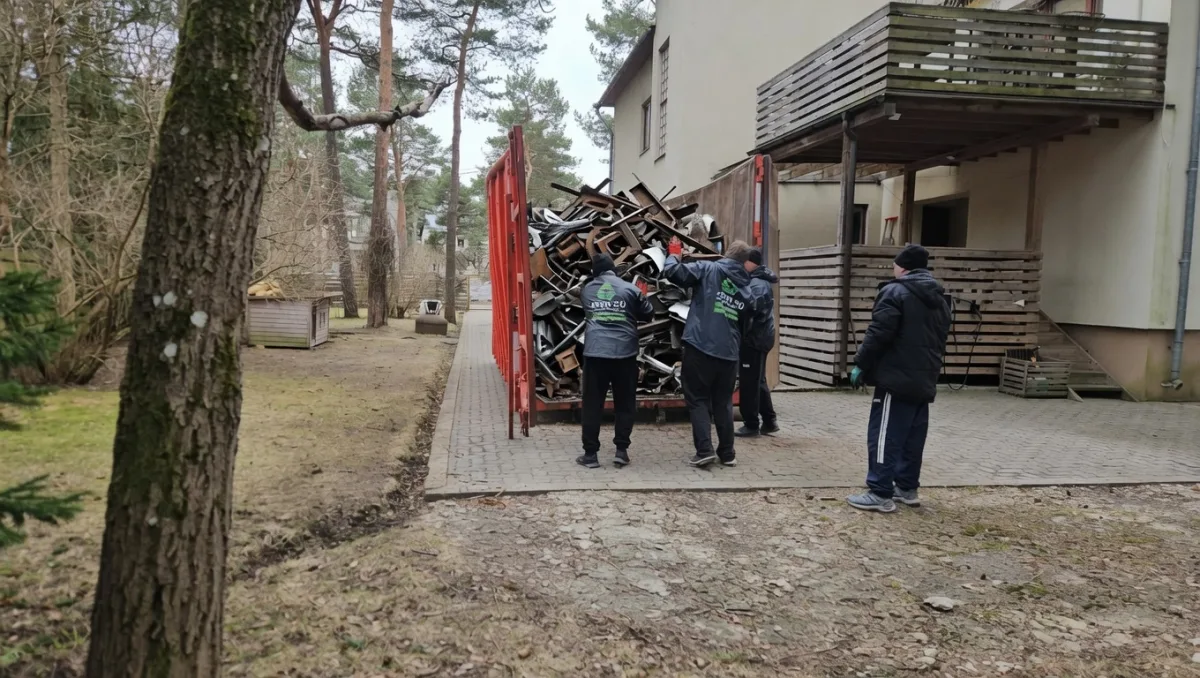 Грузчики складывают металлические профили на прицеп у дома