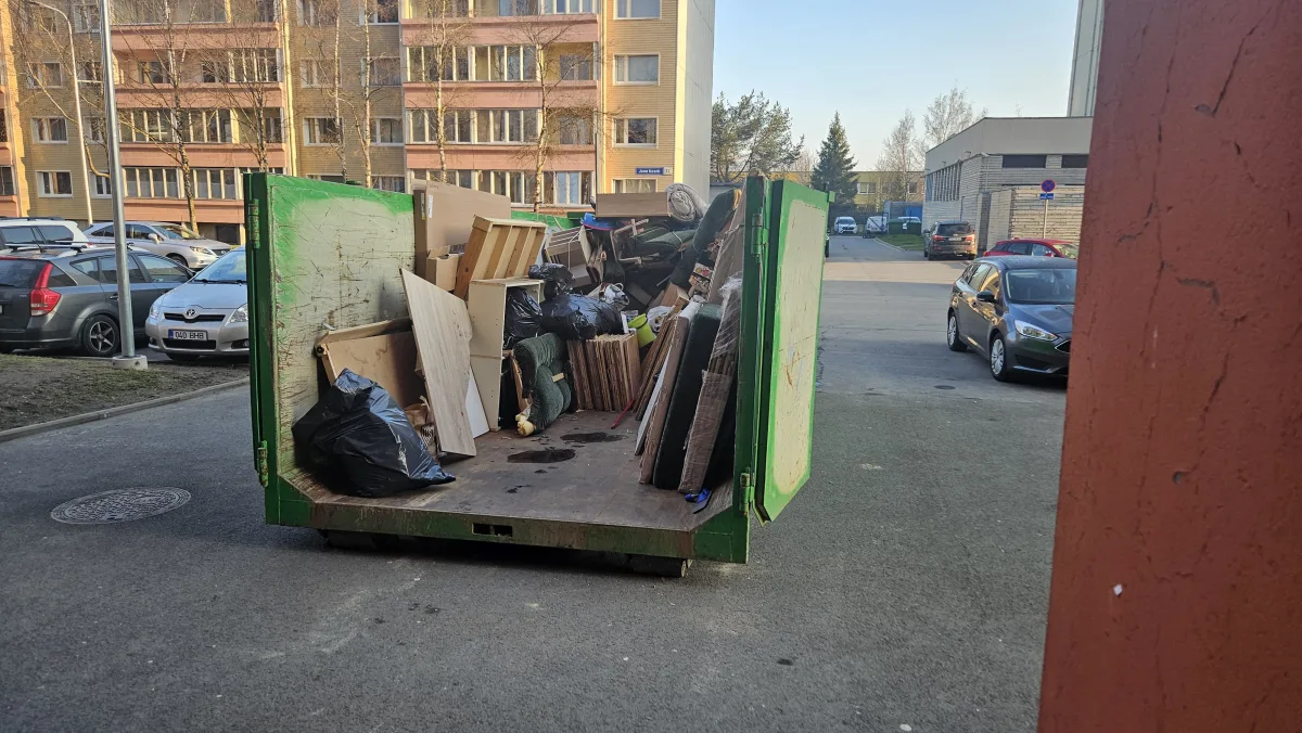 Зелёный контейнер с хламом на улице у многоэтажек