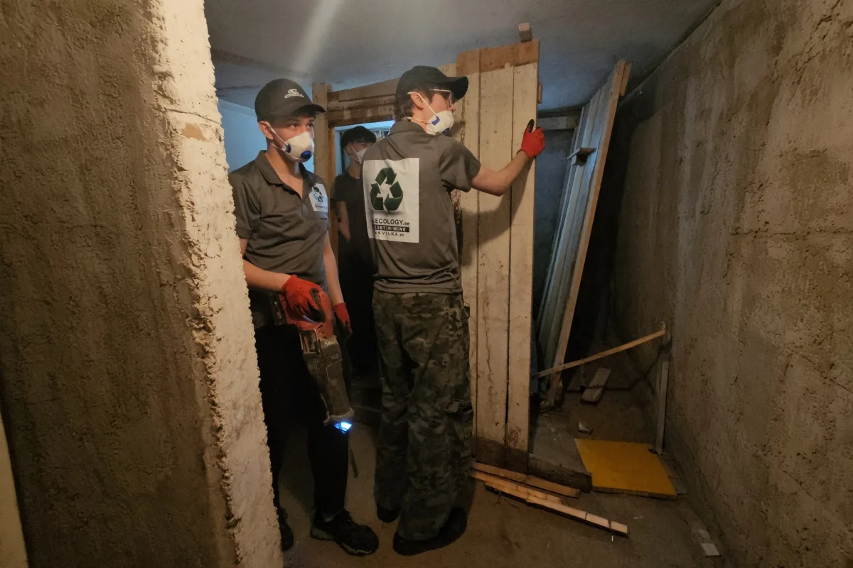 Грузчики в респираторах снимают доски с подвальной стены