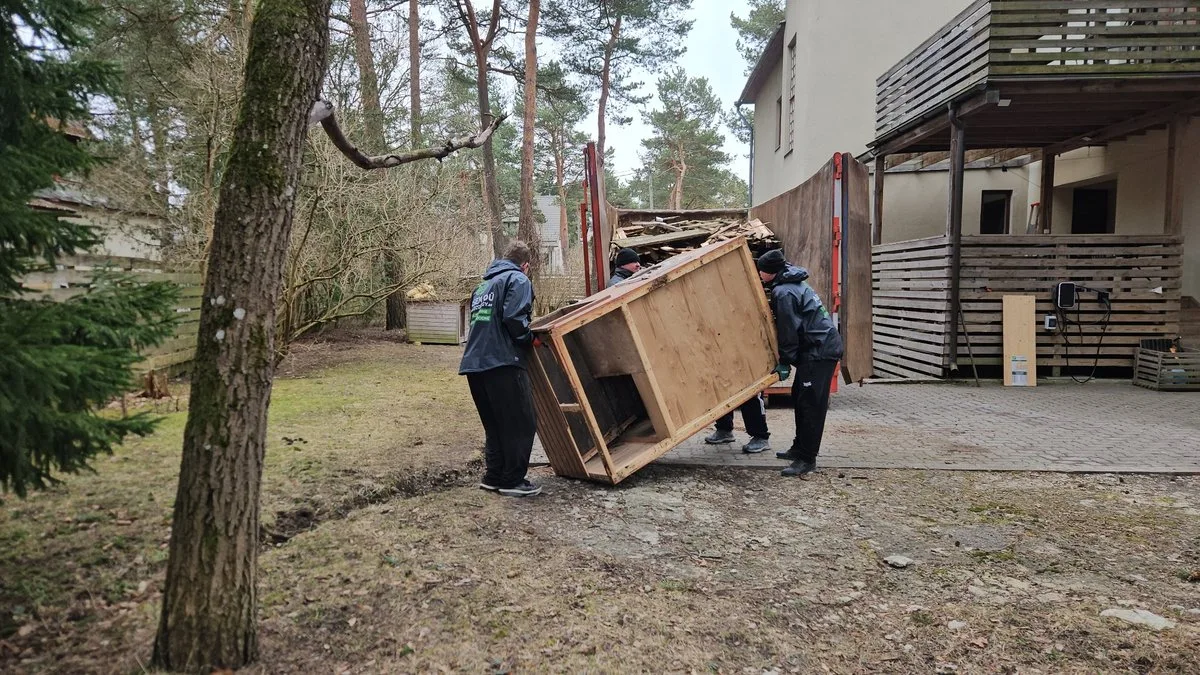 Laadijad kannavad vana kappi maja juures