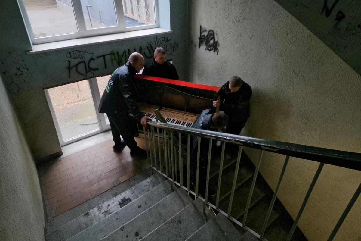 Четверо грузчиков спускают пианино по лестничному пролёту