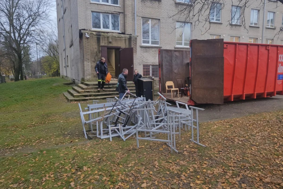 Двое у входа в дом, на газоне груда металлических рам